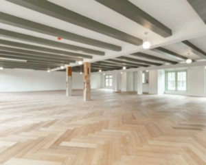 Ruime, lichte kantoorruimte met visgraat houten vloer en zichtbare plafondbalken aan de Nieuwe Herengracht 95 in Amsterdam.