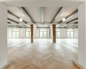 Lichte, open kantoorruimte met houten visgraatvloer en houten steunpilaren aan de Nieuwe Herengracht 95 in Amsterdam.