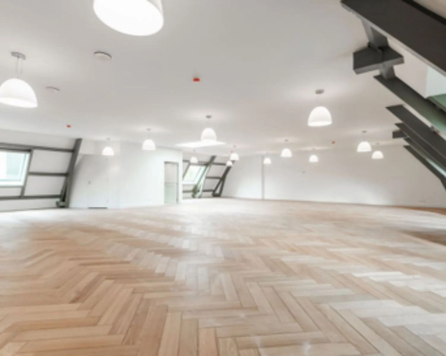 Lichte, open kantoorruimte met houten visgraatvloer en schuine ramen aan de Nieuwe Herengracht 95 in Amsterdam.