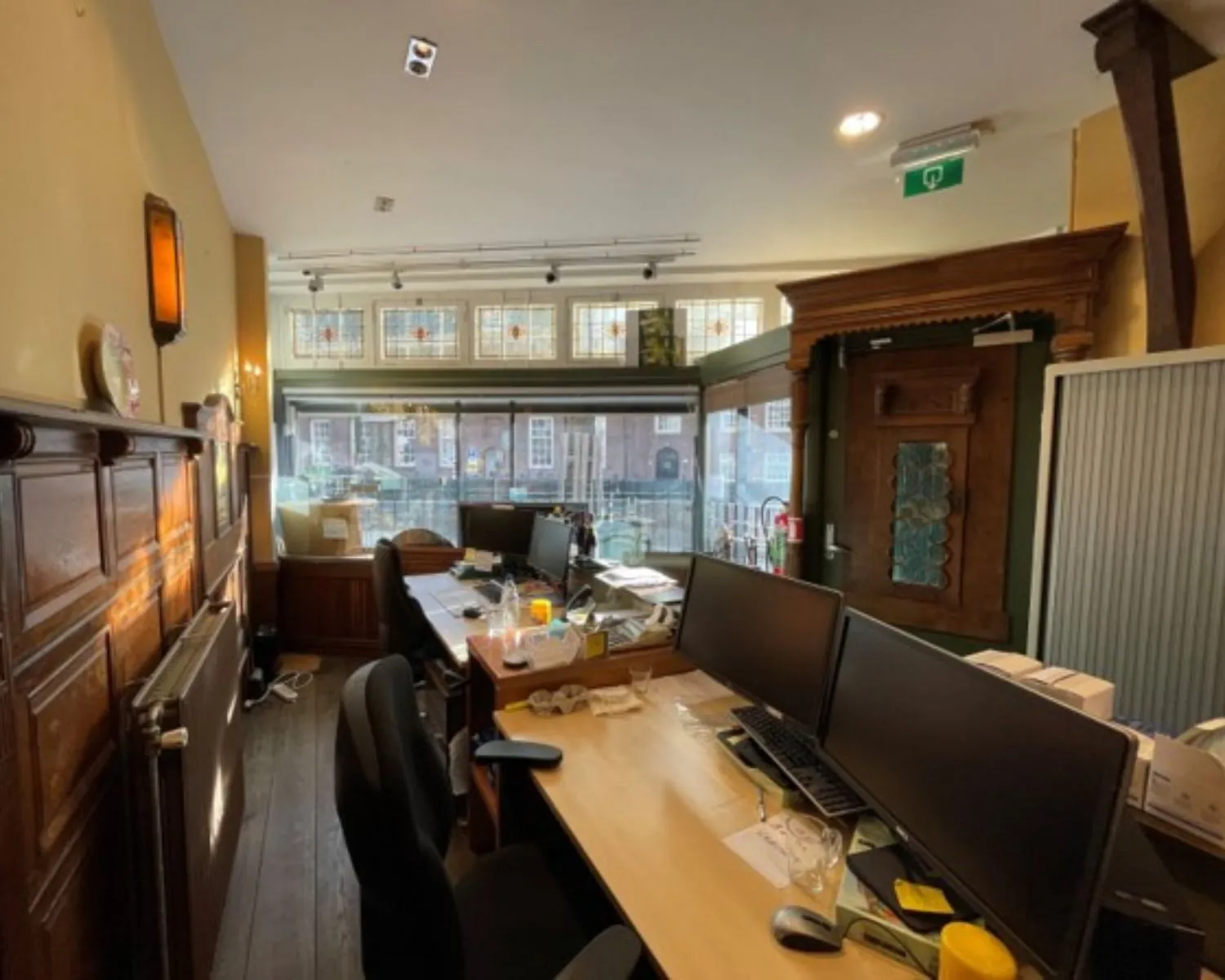 Kantoorruimte met meerdere werkplekken, houten details en glas-in-loodramen aan de Nieuwezijds Voorburgwal 314.