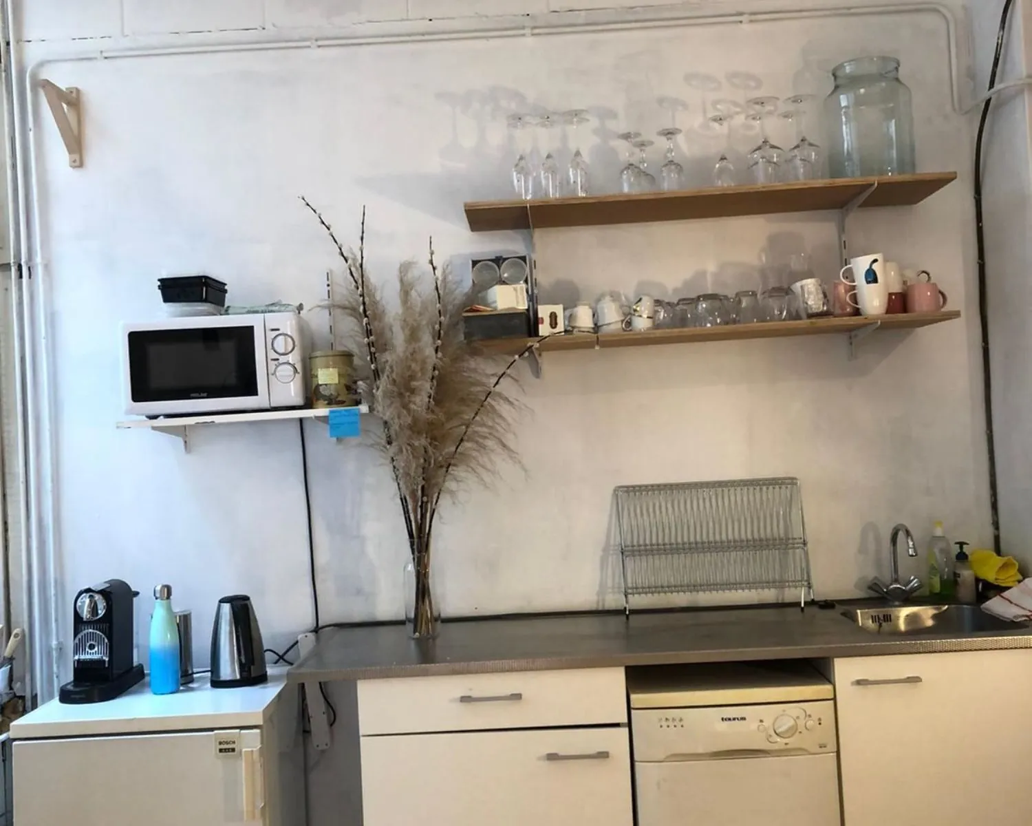 Keukenhoek met koffiezetapparaat, magnetron, wasbak en open planken in een kantoorruimte aan de Nieuwezijds Voorburgwal 340 in Amsterdam.