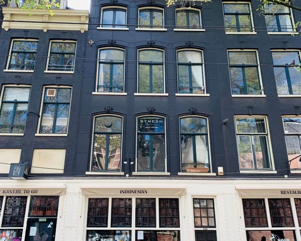 Voorgevel van een zwart pand aan de Nieuwezijds Voorburgwal 340 in Amsterdam met kantoorruimte boven de Indonesische afhaalzaak Kantjil To Go.