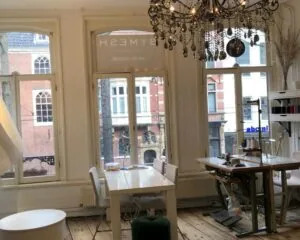 Smaakvol ingerichte kantoorruimte met naaimachines en grote ramen aan de Nieuwezijds Voorburgwal in Amsterdam.