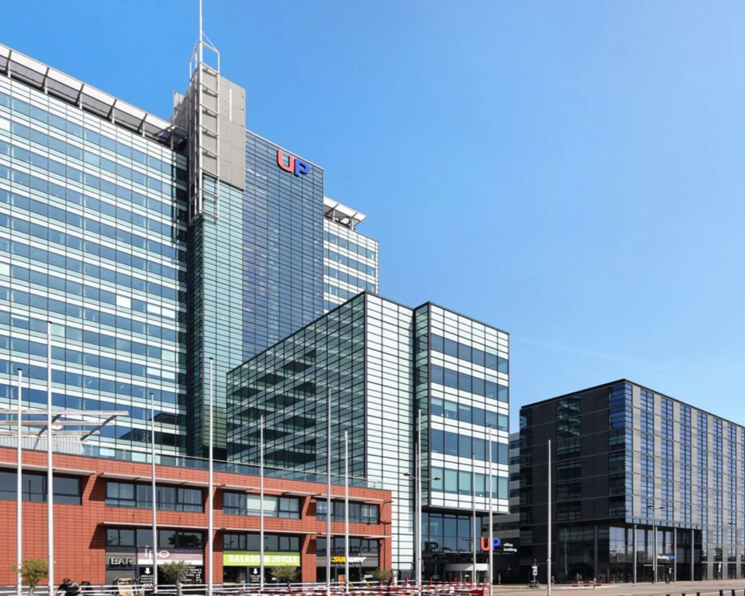 Moderne kantoorgebouwen aan de Piet Heinkade 55 in Amsterdam met glazen gevels en het UP-gebouw prominent in beeld.