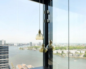 Modern kantoorinterieur met hanglampen en panoramisch uitzicht over het IJ vanaf Piet Heinkade 55 in Amsterdam.