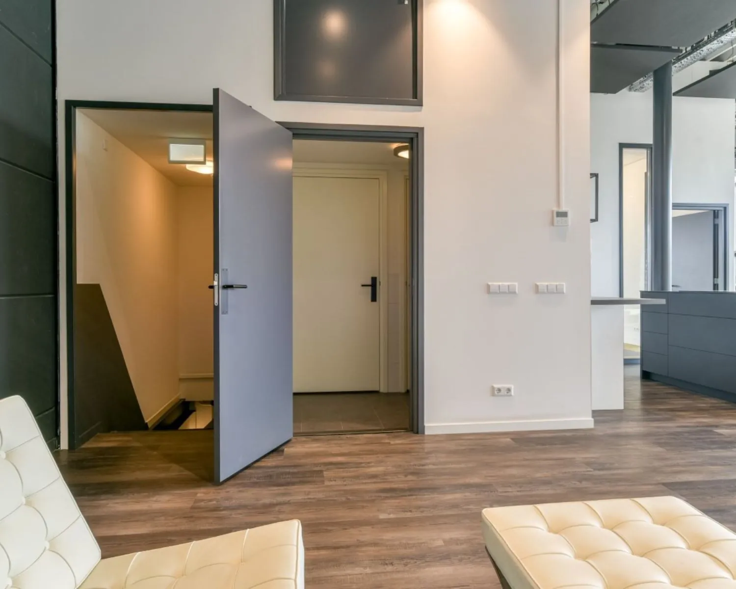 Moderne kantoorruimte in Poortland 242 met open deuren, houten vloer en minimalistische inrichting.