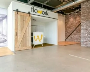 Moderne kantoorruimte bij Flowork aan Poortland 242 met industriële details en houten schuifdeur.