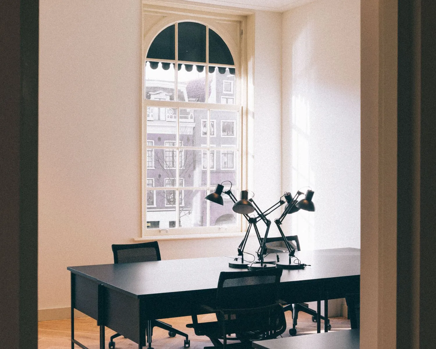 Moderne kantoorruimte aan de Prinsengracht in Amsterdam met grote ramen, bureaus en bureaulampen.