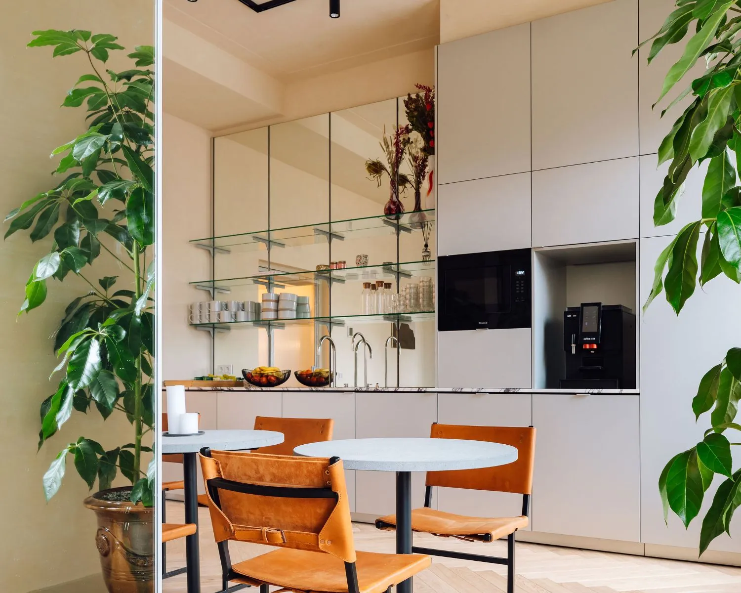 Moderne pantry met koffieautomaat, ronde tafels en leren stoelen in een kantoorruimte aan de Prinsengracht 769 in Amsterdam.
