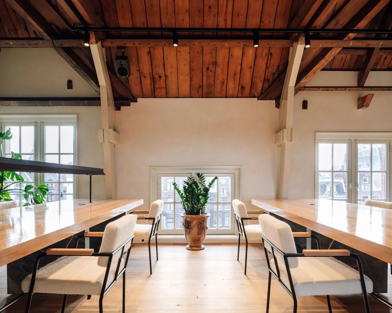 Moderne kantoorruimte met houten balkenplafond en grote ramen aan de Prinsengracht in Amsterdam.
