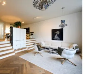 Moderne kantoorruimte aan de Sarphatistraat in Amsterdam met een stijlvolle zithoek, designmeubilair en houten visgraatvloer.