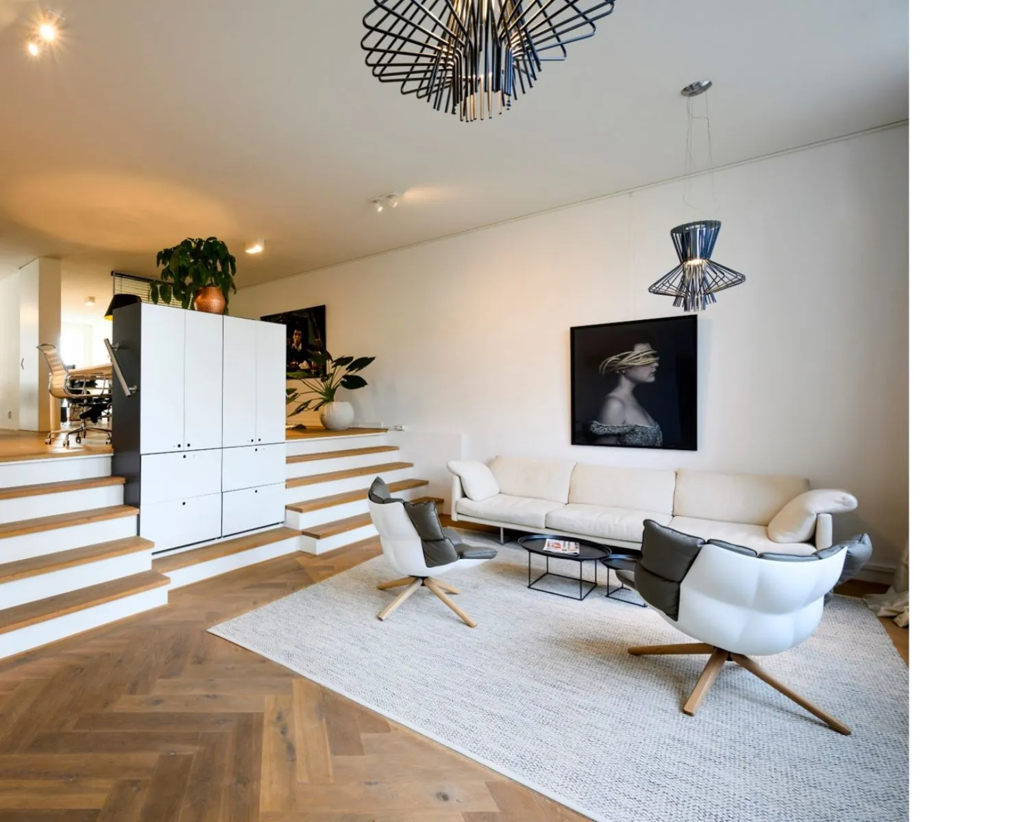 Moderne kantoorruimte aan de Sarphatistraat in Amsterdam met een stijlvolle zithoek, designmeubilair en houten visgraatvloer.