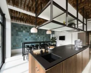 Moderne kantoorkeuken op Sloterweg 796 in Amsterdam met strak zwart keukeneiland, hoge zitplekken en decoratieve wand- en plafondafwerking.