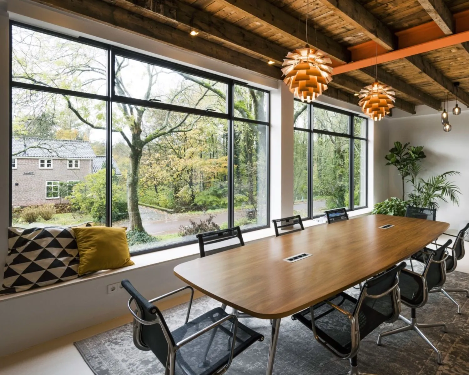 Moderne vergaderruimte met houten tafel, designstoelen en grote ramen aan de Sloterweg 796 in Amsterdam.