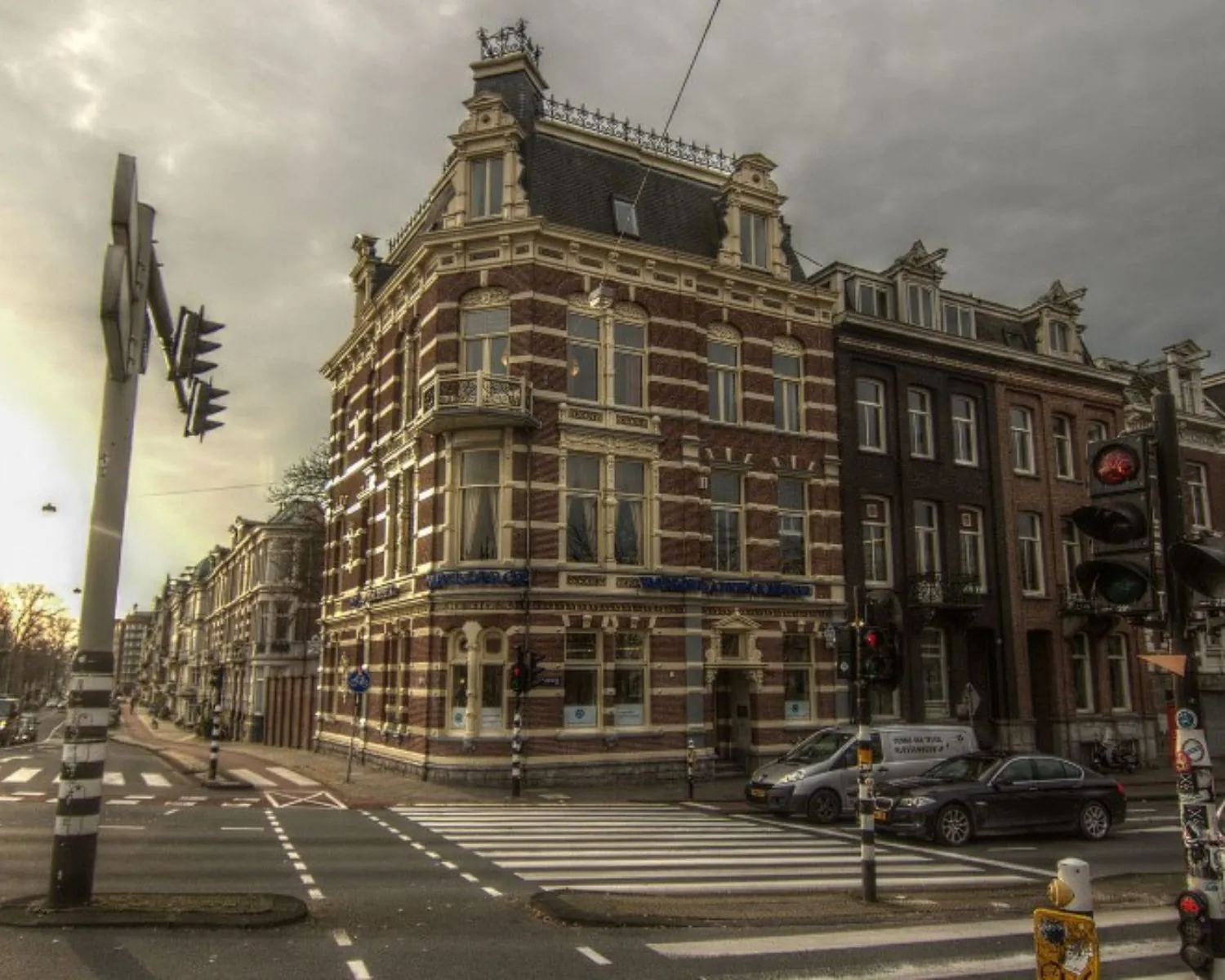 Historisch kantoorpand aan de Stadhouderskade 160 in Amsterdam op een hoek met zebrapad en verkeer.
