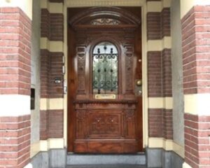 Houten voordeur met sierlijk houtsnijwerk en smeedijzeren rooster aan de Stadhouderskade 160 in Amsterdam.