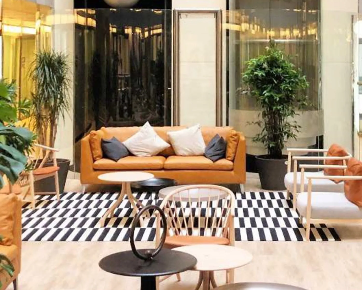 Moderne, open kantoorlounge met stijlvolle zitbanken, planten en een zwart-wit gestreept vloerkleed bij TNW.