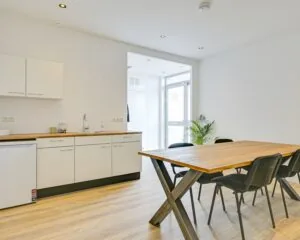 Moderne kantoorruimte aan Tijnmuiden 89 in Amsterdam met een keukenblok en vergadertafel.