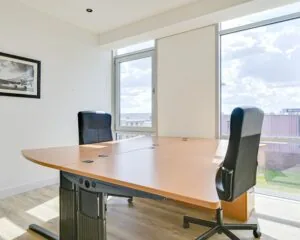 Lichte en moderne kantoorruimte met twee bureaustoelen en een groot houten bureau bij Tijnmuiden 89 in Amsterdam.