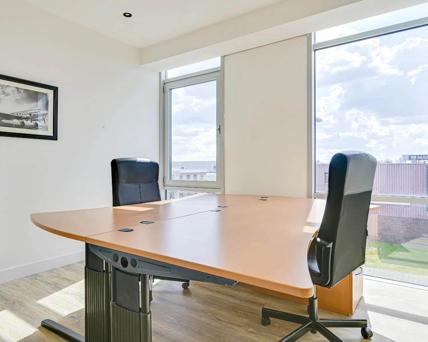 Lichte en moderne kantoorruimte met twee bureaustoelen en een groot houten bureau bij Tijnmuiden 89 in Amsterdam.