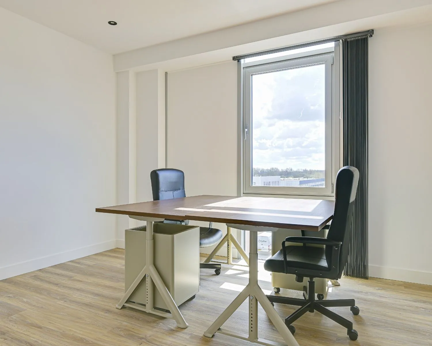Lichte en moderne kantoorruimte met twee bureaustoelen en een groot raam aan Tijnmuiden 89 in Amsterdam.