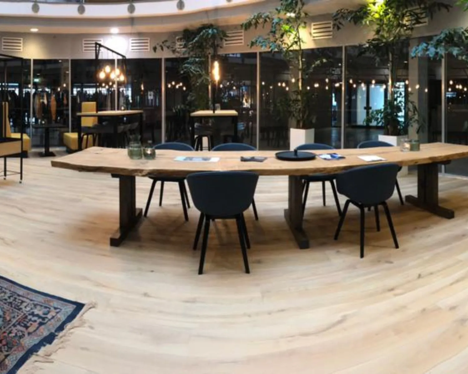 Moderne kantoorruimte aan de Veluwezoom in Almere met een lange houten vergadertafel, blauwe stoelen en veel groen.