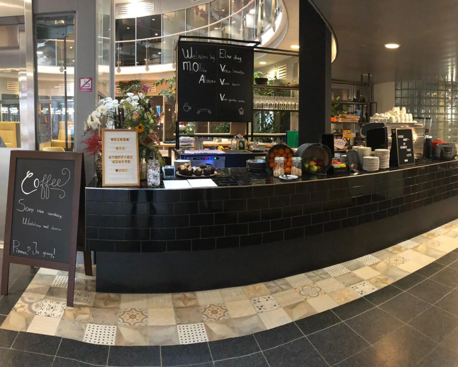 Moderne koffie- en lunchbar in de kantoorruimte aan Veluwezoom 5 in Almere met zwarte tegelbalie en menuborden.