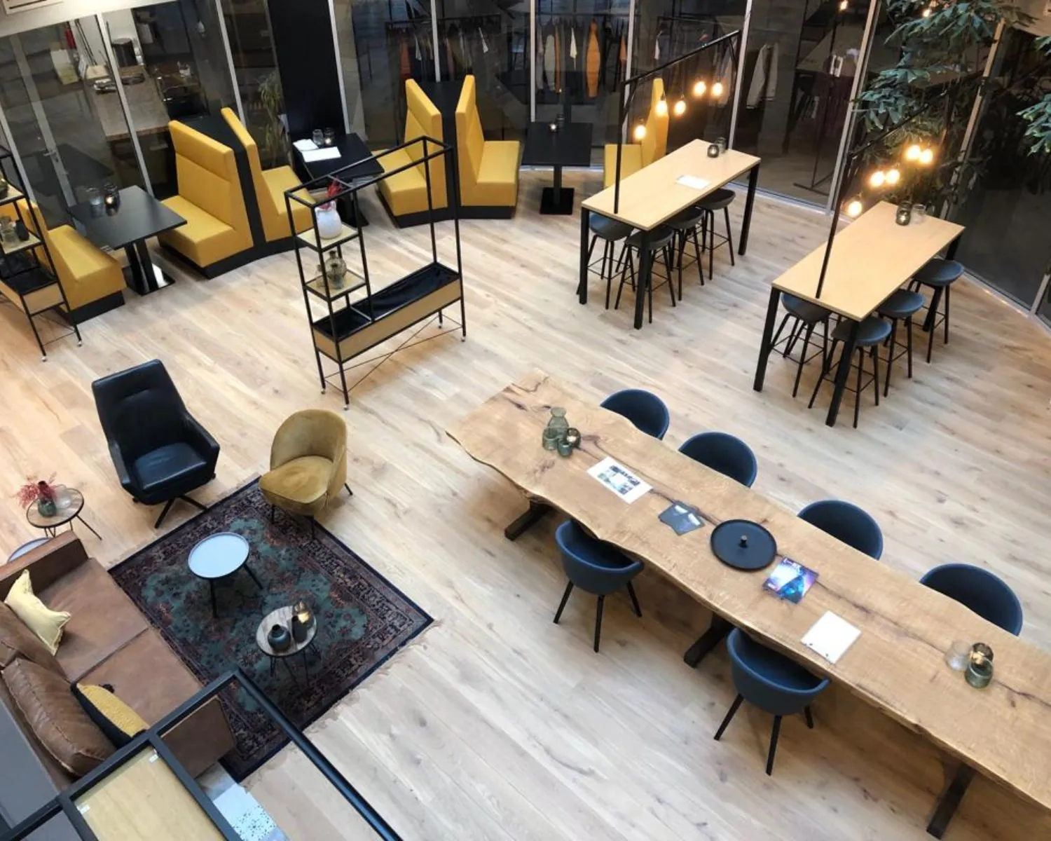 Moderne kantoorruimte in Veluwezoom 5 Almere met houten vloeren, lange vergadertafel, loungehoek en gele zithoeken.