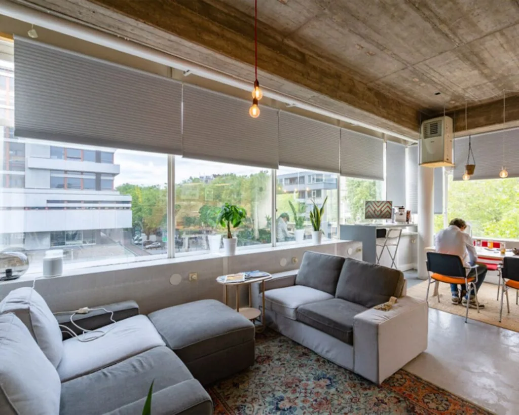 Moderne kantoorruimte aan de Vijverhofstraat 47 in Rotterdam met loungehoek, grote ramen en uitzicht op omliggende gebouwen.