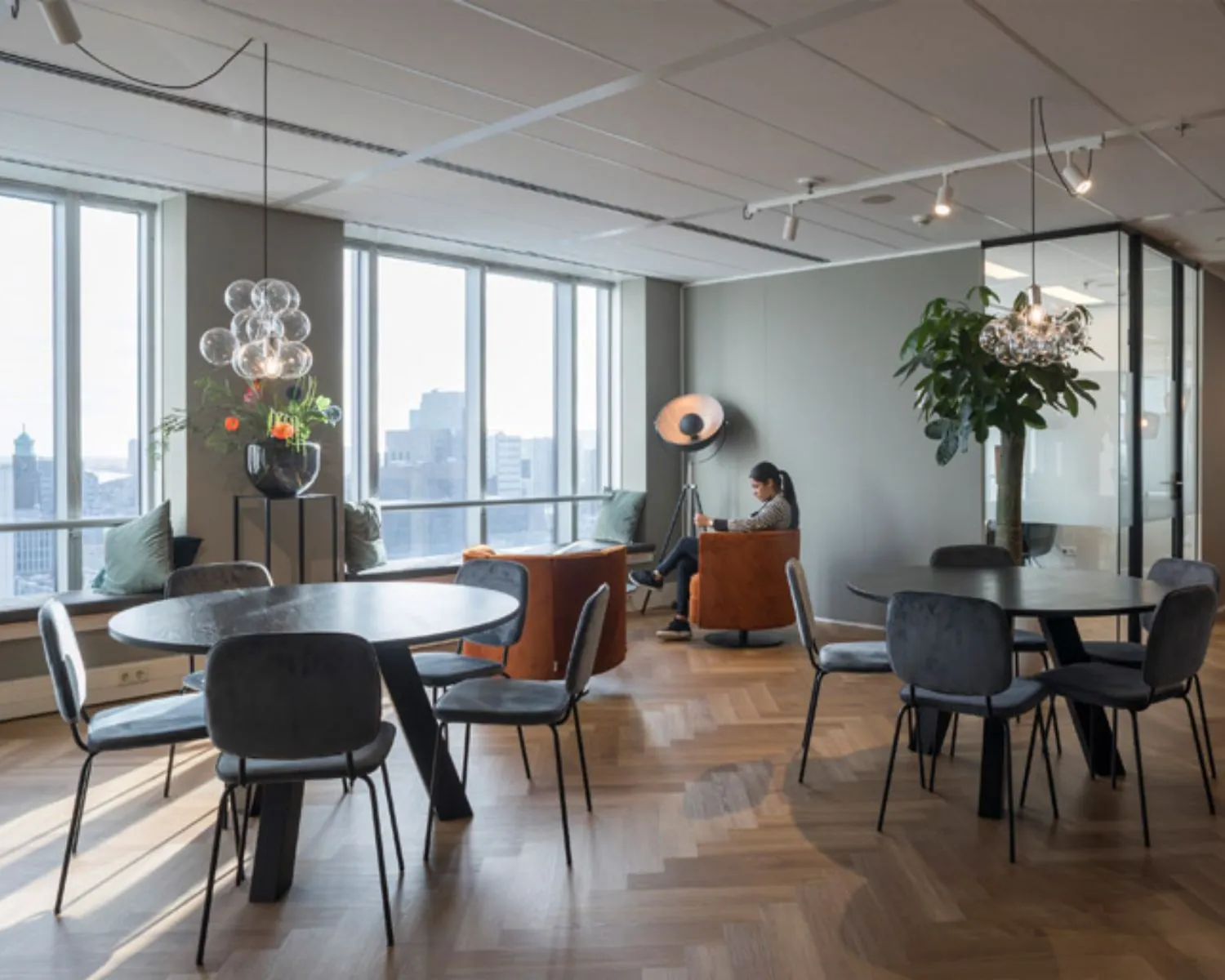 Moderne en licht ingerichte kantoorruimte aan Weena 690 in Rotterdam met zitjes, ronde tafels en uitzicht op de stad.