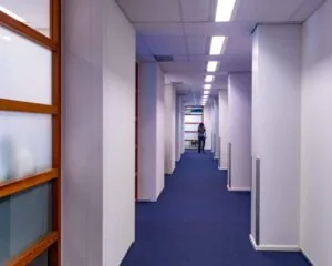 Geverfde gang met blauwe vloerbedekking en witte wanden in een kantoorruimte aan Westblaak 92 in Rotterdam.