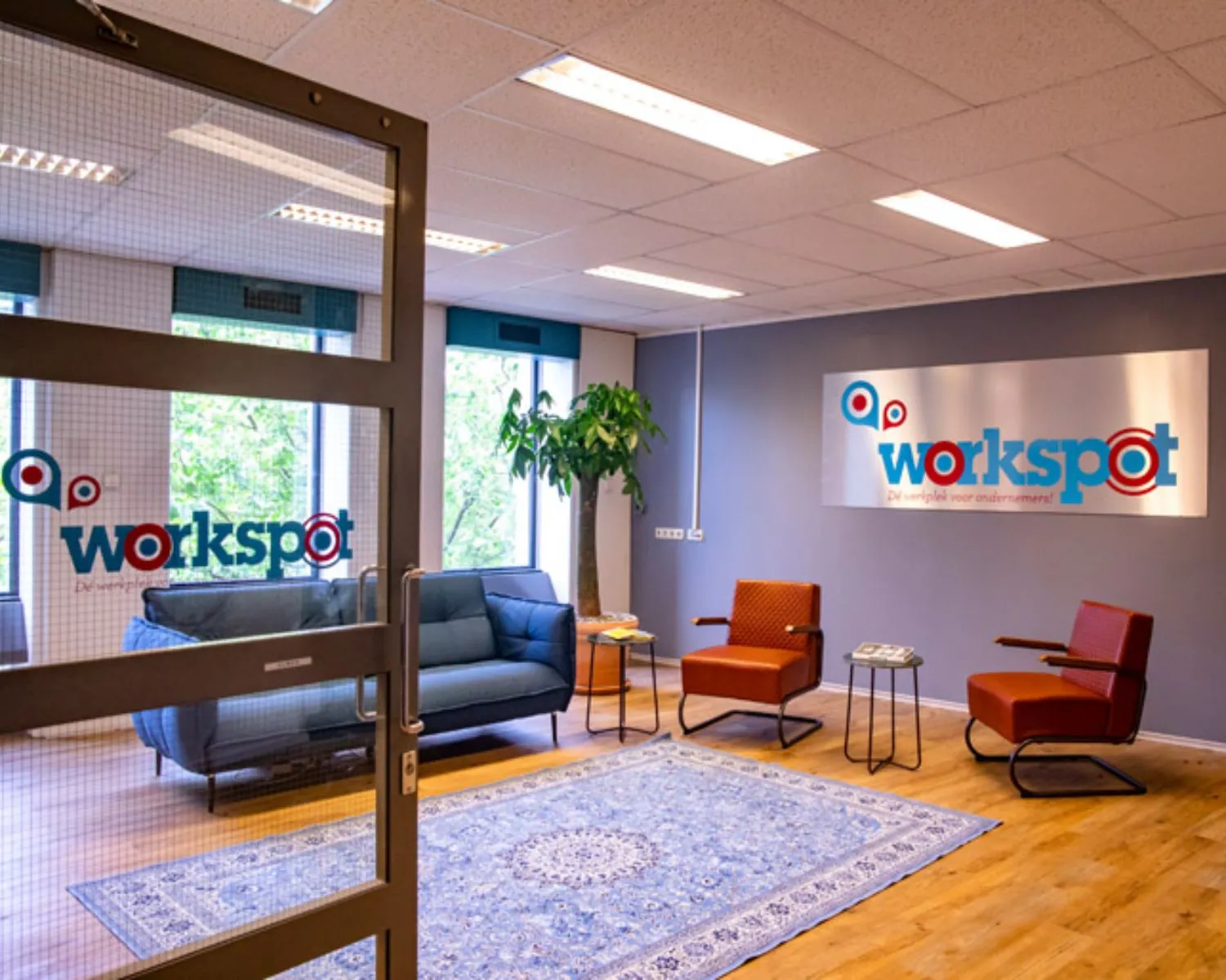 Moderne en kleurrijke wachtruimte van kantoorruimte Workspot aan de Westblaak 92 in Rotterdam met zithoek, vloerkleed en grote raampartijen.