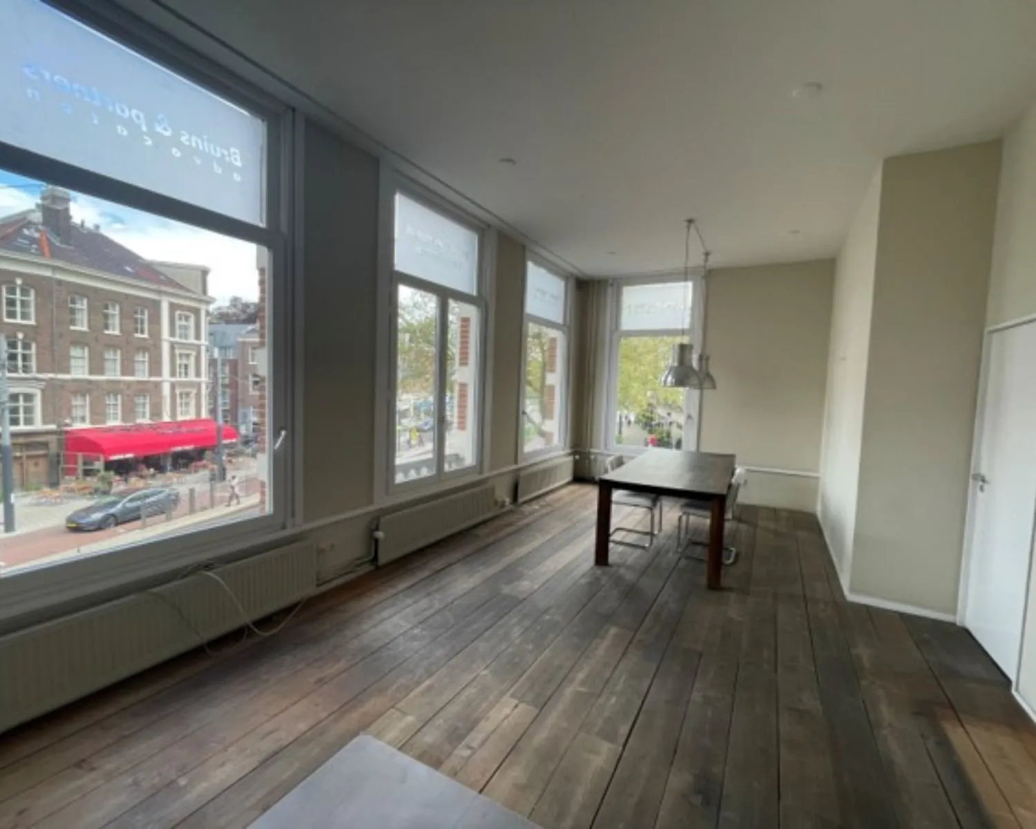 Lichte kantoorruimte aan de Weteringschans 130 in Amsterdam met houten vloer, grote ramen en uitzicht op de straat.