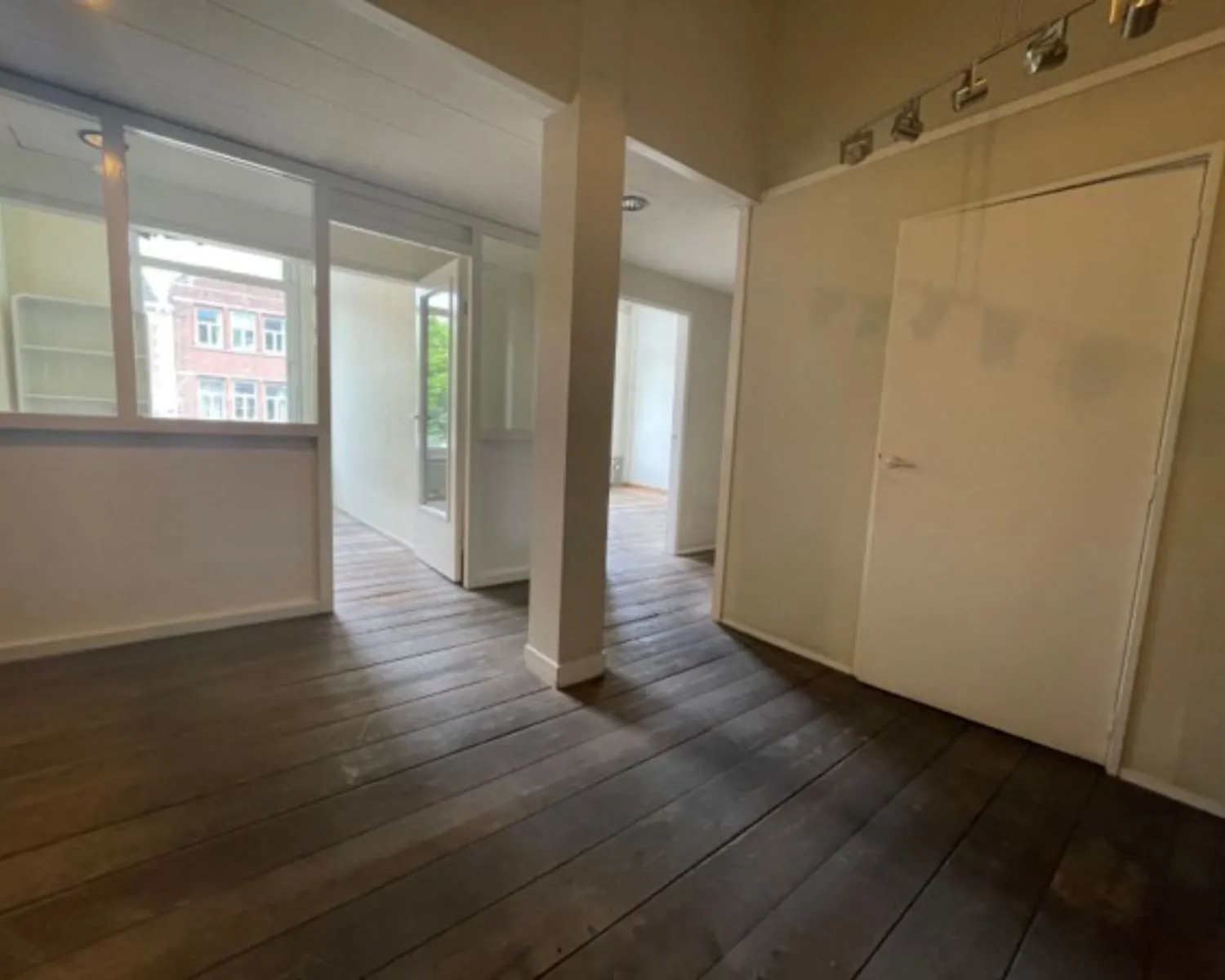 Binnenruimte van een kantoor aan de Weteringschans 130 in Amsterdam met houten vloer, witte wanden en glazen scheidingswanden.