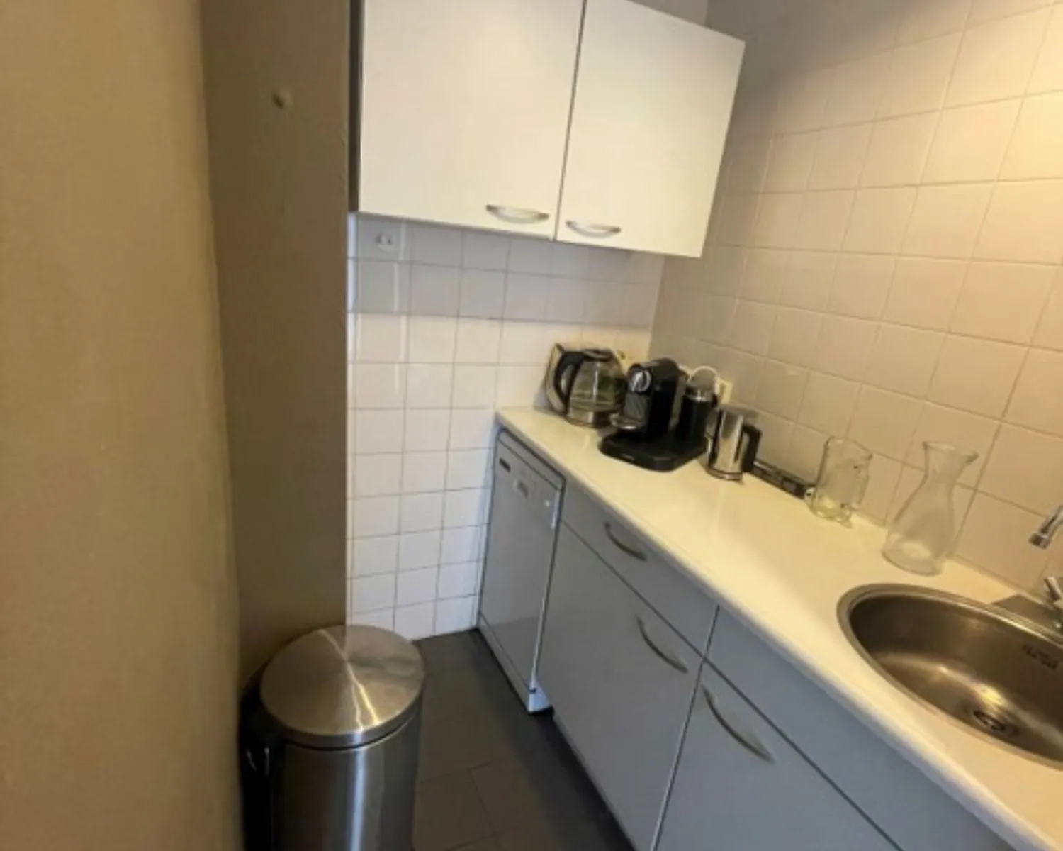 Kleine pantry in kantoorruimte aan de Weteringschans 130 in Amsterdam met koffiezetapparaten, gootsteen en witte kasten.