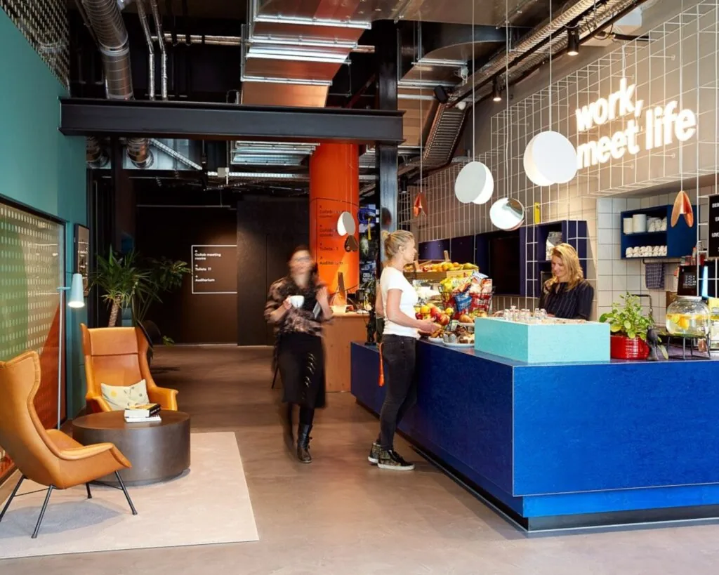 Moderne kantoorruimte aan de Wibautstraat 131 met een kleurrijke koffiebar en zitgedeelte.