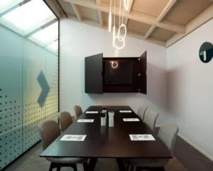 Moderne vergaderruimte aan de Wibautstraat 131 met minimalistisch interieur, glazen wand en houten tafel.