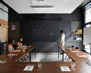 Moderne vergaderruimte aan de Wibautstraat 131 met schrijfmuur, houten tafels en creatieve sfeer.