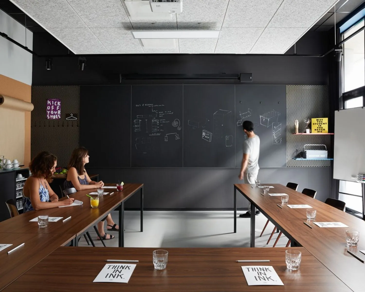 Moderne vergaderruimte aan de Wibautstraat 131 met schrijfmuur, houten tafels en creatieve sfeer.
