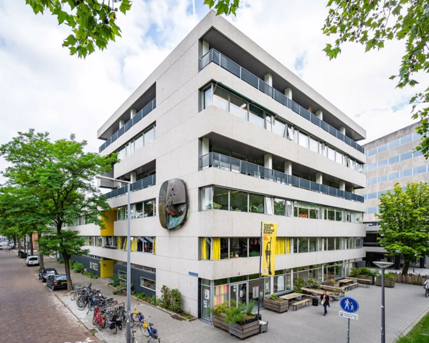 Modern kantoorgebouw aan de Zomerhofstraat 84 in Rotterdam met grote ramen, terrastafels en opvallende gevelkunst.