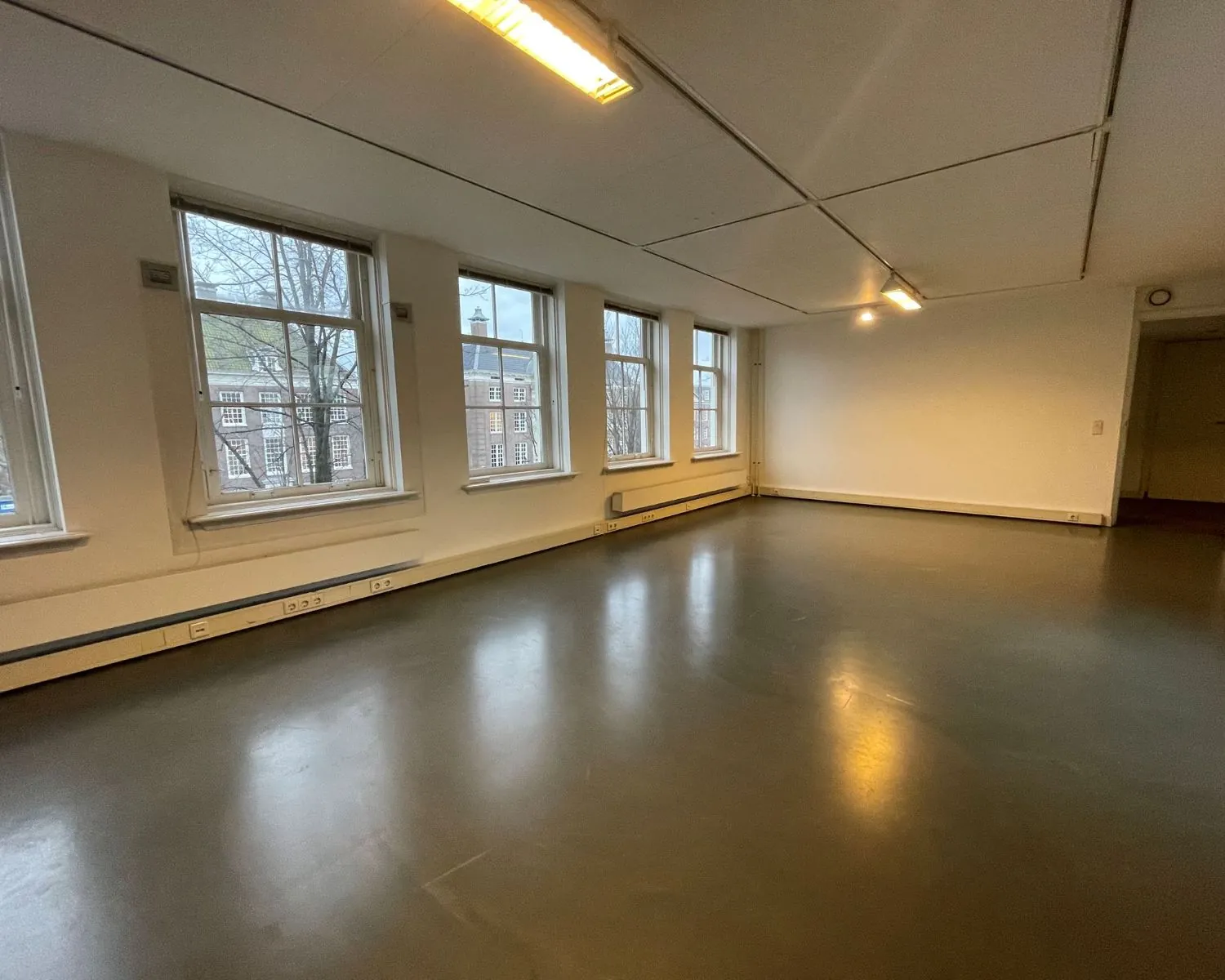 Lichte, lege kantoorruimte met grote ramen aan de Nieuwe Herengracht 51 in Amsterdam.