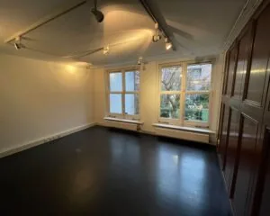 Lichte kantoorruimte met grote ramen en uitzicht op een tuin aan de Nieuwe Herengracht 51 in Amsterdam.