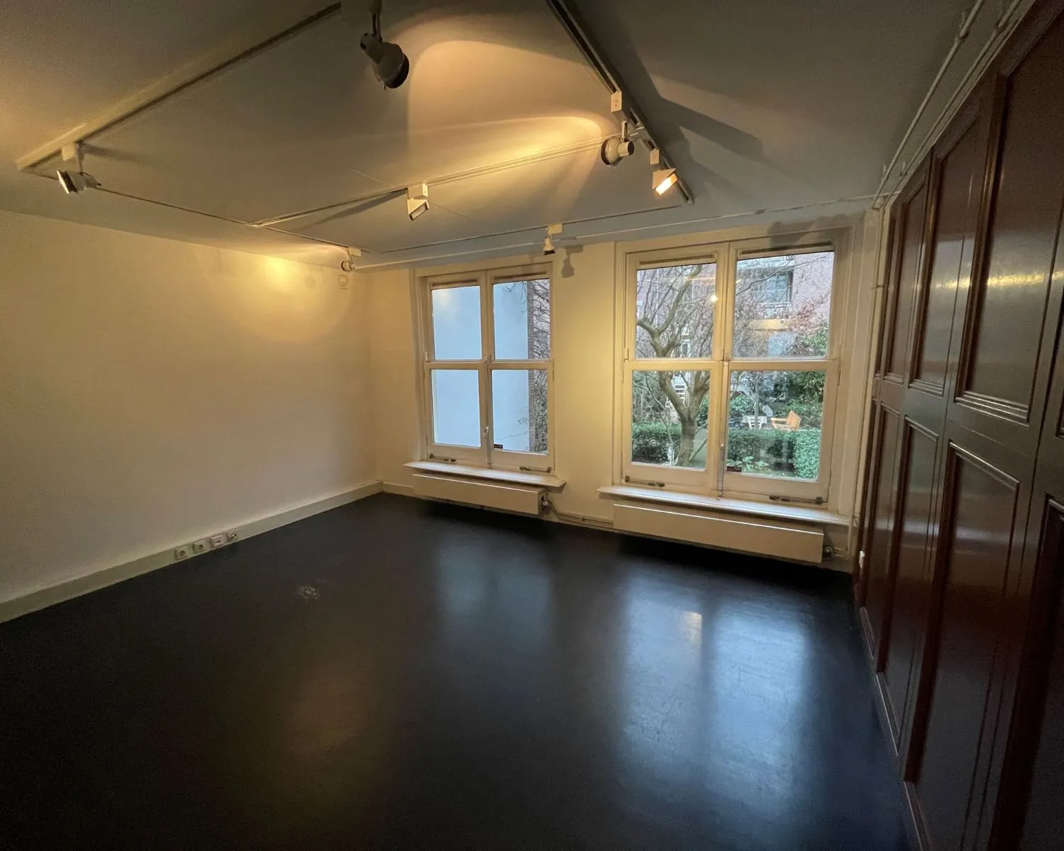 Lichte kantoorruimte met grote ramen en uitzicht op een tuin aan de Nieuwe Herengracht 51 in Amsterdam.