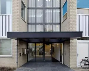 Ingang van een modern kantoorgebouw aan de Regulierenring 2 in Bunnik met glazen deuren en overkapping.