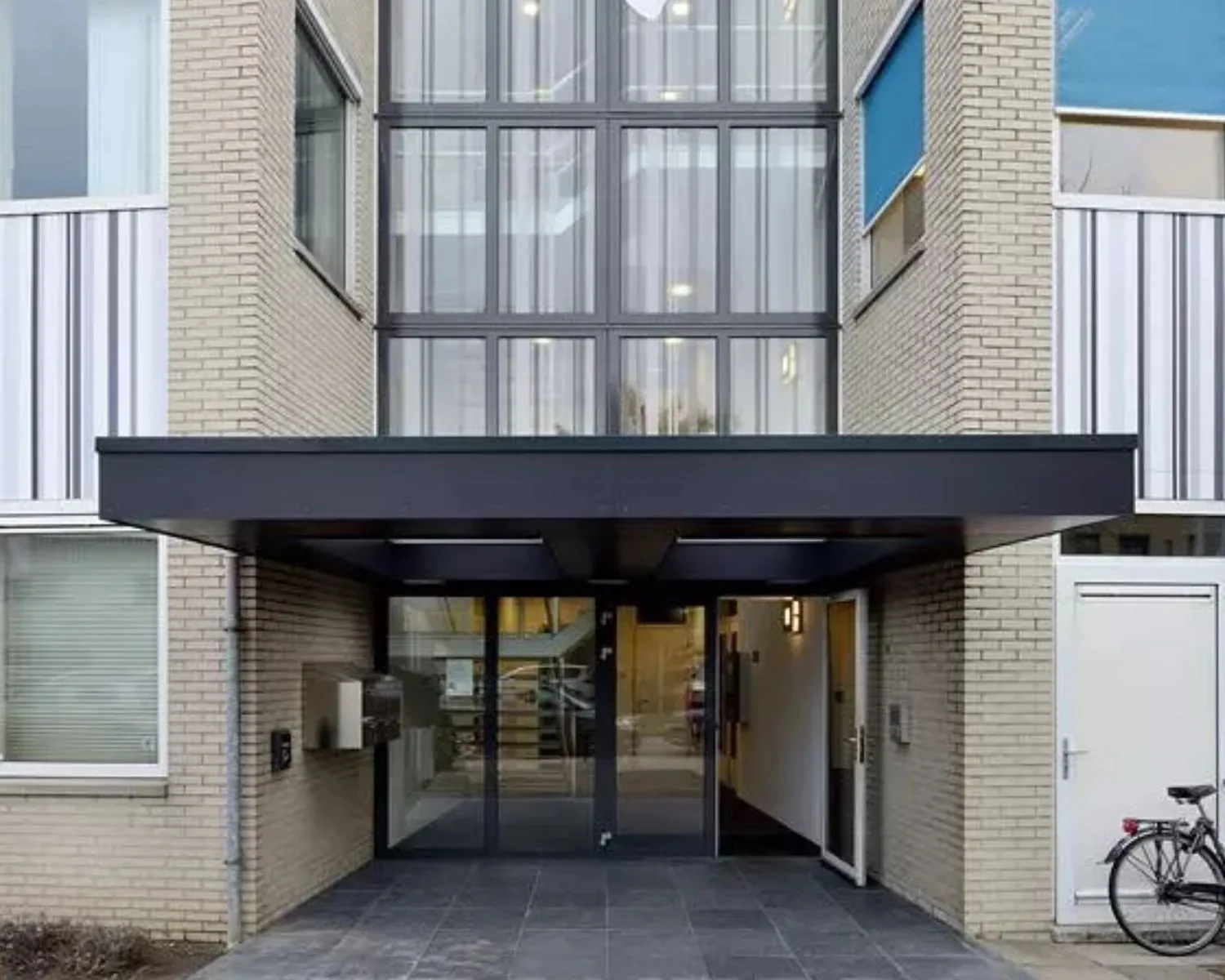 Ingang van een modern kantoorgebouw aan de Regulierenring 2 in Bunnik met glazen deuren en overkapping.