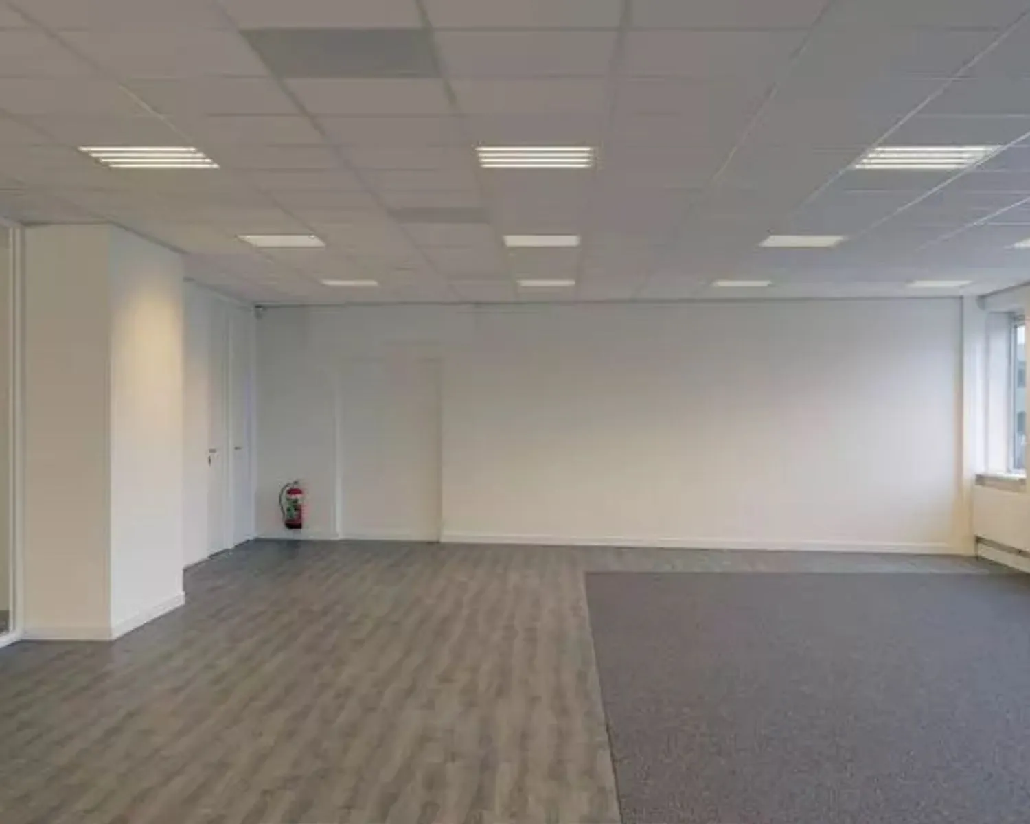 Lege kantoorruimte met systeemplafond, houtlook vloer en tapijttegels aan de Regulierenring 2 in Bunnik.