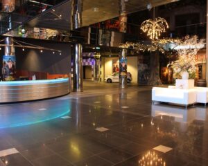 Moderne en ruime kantoorlobby aan de Van Cleeffkade 15 met glanzende vloertegels, een ronde receptiebalie en sfeervolle verlichting.