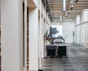 Moderne kantoorruimte aan de Van Cleeffkade 15 met open werkplekken, bloemen en een gemeenschappelijke keuken.