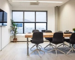 Modern ingerichte vergaderruimte met houten tafel en zes stoelen aan de Van Cleeffkade 15.