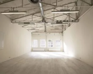 Lichte, lege kantoorruimte met hoog plafond en zichtbare ventilatiebuizen aan de Van Cleeffkade 15.